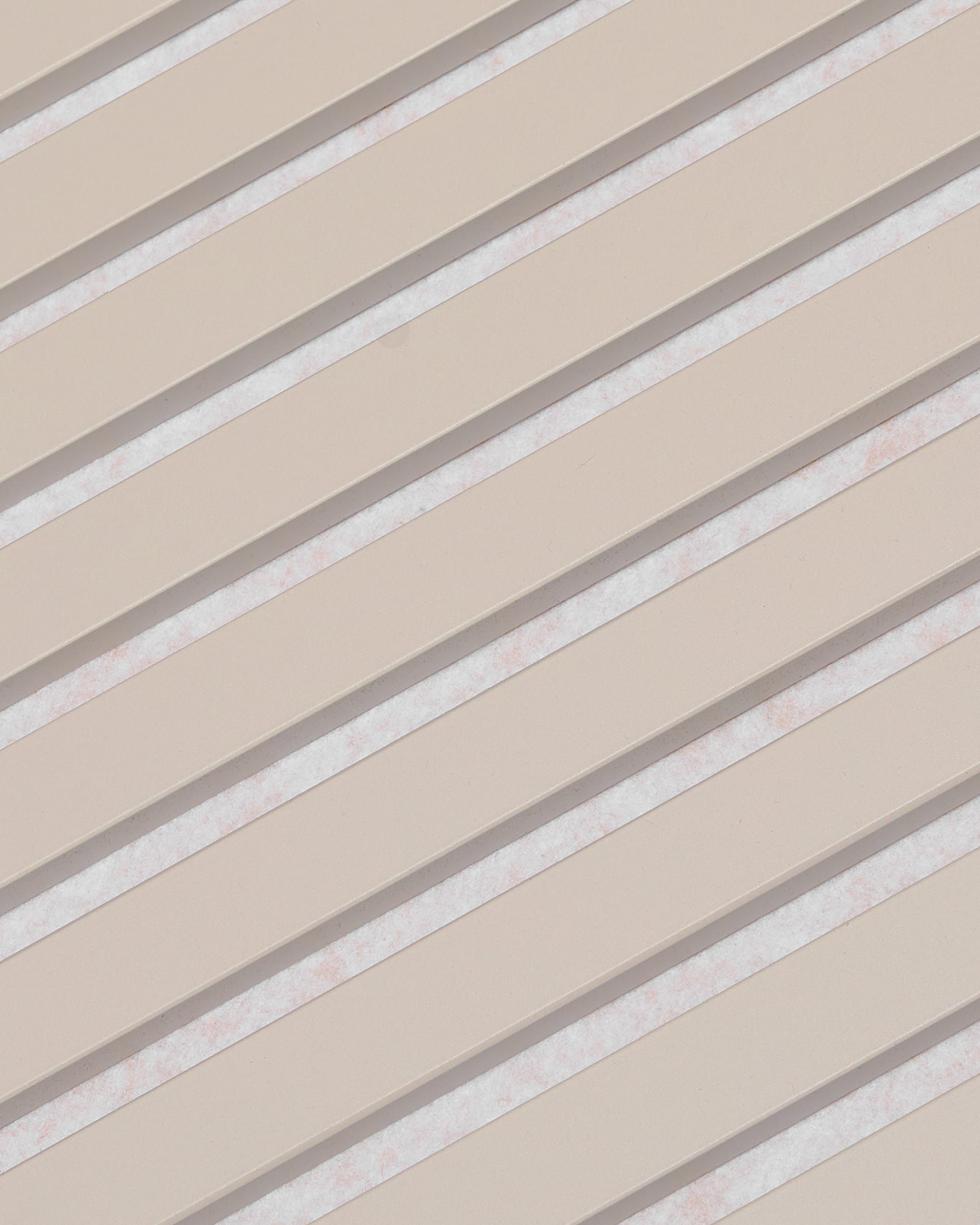 Ukośne beżowe listwy z białymi przerwami tworzą wzór w paski na panelu akustycznym WoodUpp Akupanel, wykończonym filcem w kolorze Soft Linen Light Beige, o wymiarach 240 x 60 cm.